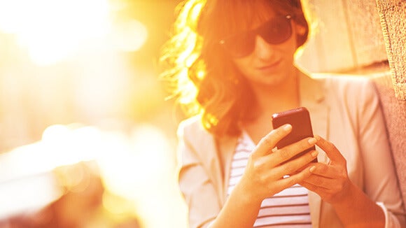 woman with sunglasses on using mobile phone woman outside with sunglasses on in sunshine using mobile phone