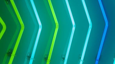 green and blue neon arrow lights pointing right on green background